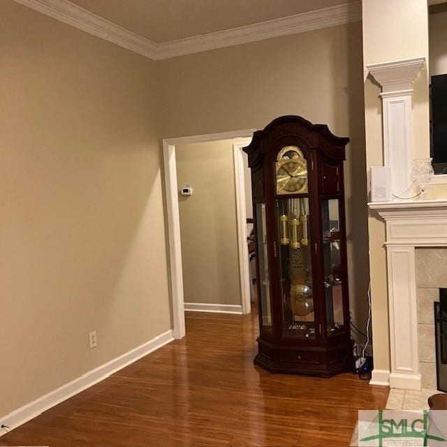 interior space with a tiled fireplace, crown molding, and wood-type flooring