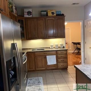 kitchen with light tile patterned floors and stainless steel fridge