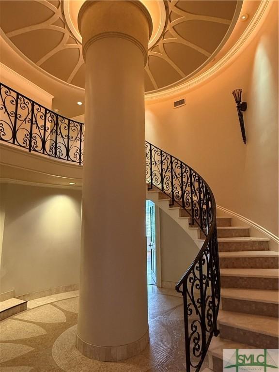 stairs with ornamental molding and a high ceiling