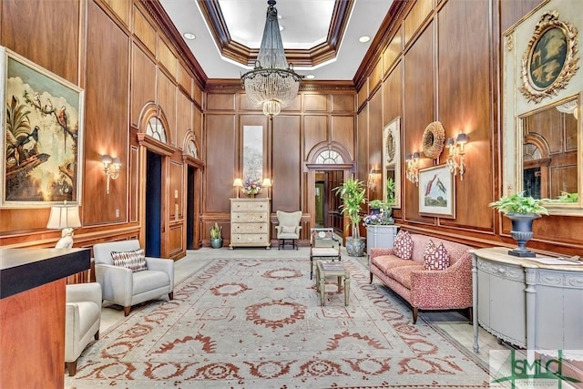 living area with an inviting chandelier, a decorative wall, a high ceiling, and ornamental molding