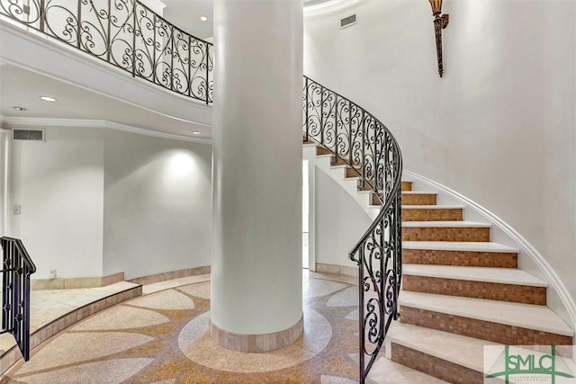 stairs featuring baseboards, visible vents, recessed lighting, ornamental molding, and a towering ceiling