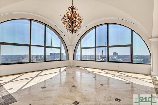 unfurnished room featuring high vaulted ceiling, an inviting chandelier, a view of city, and baseboards