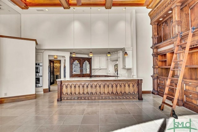 interior space featuring a high ceiling, baseboards, and a sink