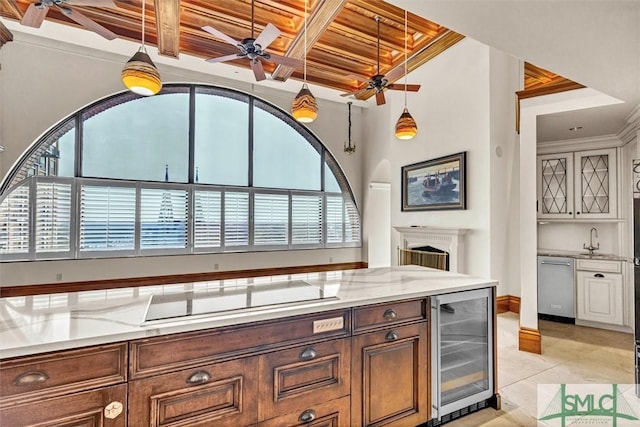 kitchen featuring cooktop, light stone countertops, beverage cooler, and a fireplace