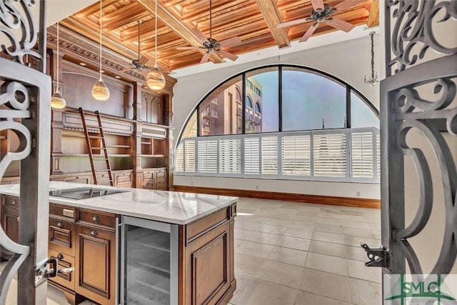 interior space with wine cooler, coffered ceiling, ceiling fan, and brown cabinetry