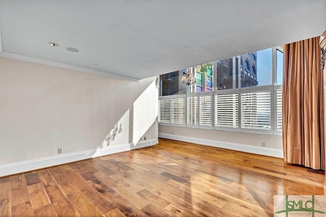 spare room featuring baseboards, wood finished floors, and ornamental molding