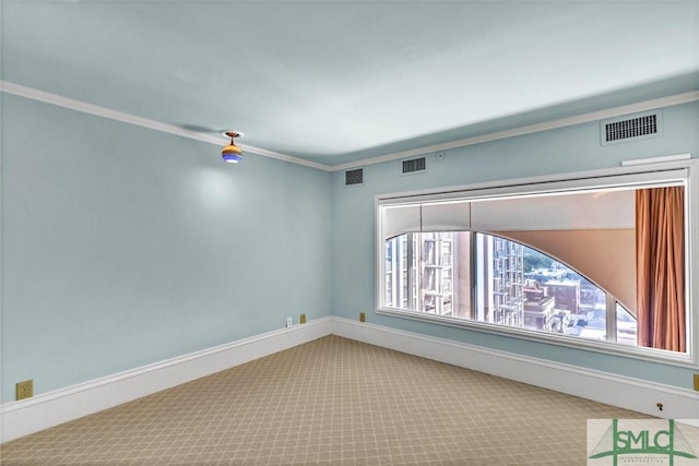 carpeted empty room featuring visible vents, baseboards, and crown molding