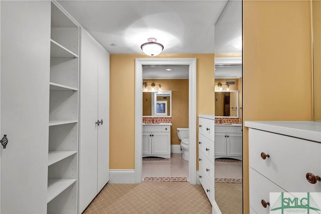 spacious closet with light tile patterned floors and a sink