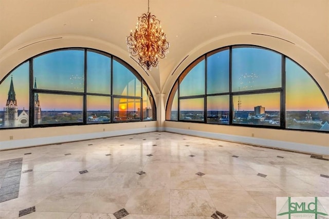 spare room featuring a chandelier, a city view, baseboards, and vaulted ceiling