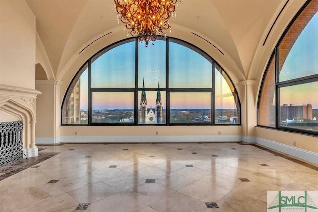 interior space with lofted ceiling, a large fireplace, baseboards, and a chandelier