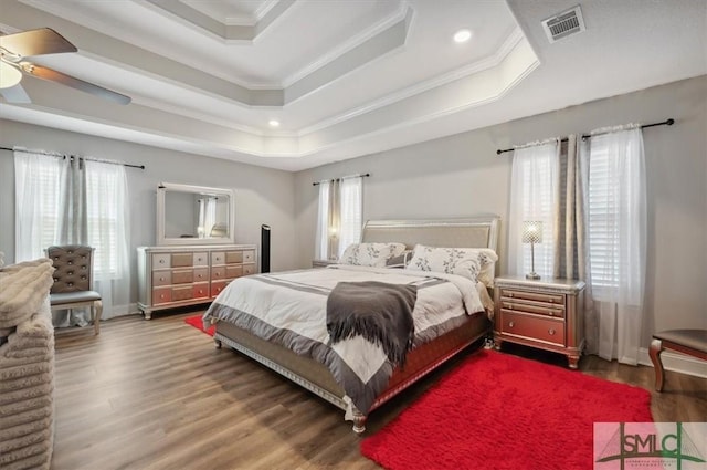 bedroom featuring hardwood / wood-style flooring, ceiling fan, ornamental molding, and a tray ceiling