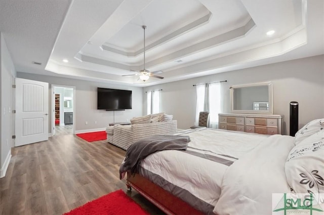 bedroom with ceiling fan, ornamental molding, a raised ceiling, and hardwood / wood-style floors