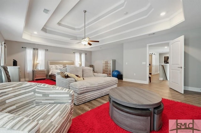 bedroom featuring a raised ceiling, crown molding, hardwood / wood-style flooring, and ceiling fan