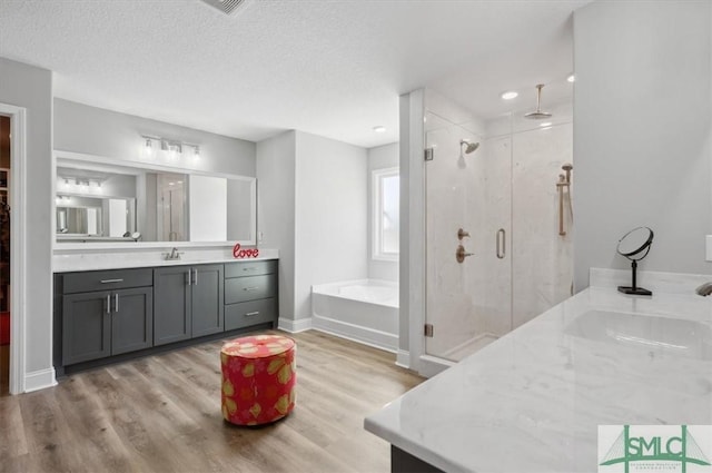 bathroom with hardwood / wood-style flooring, vanity, independent shower and bath, and a textured ceiling