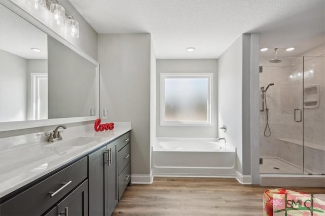 bathroom with vanity, plus walk in shower, hardwood / wood-style floors, and a textured ceiling