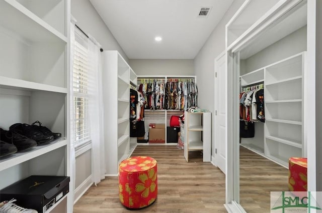 walk in closet with light hardwood / wood-style flooring