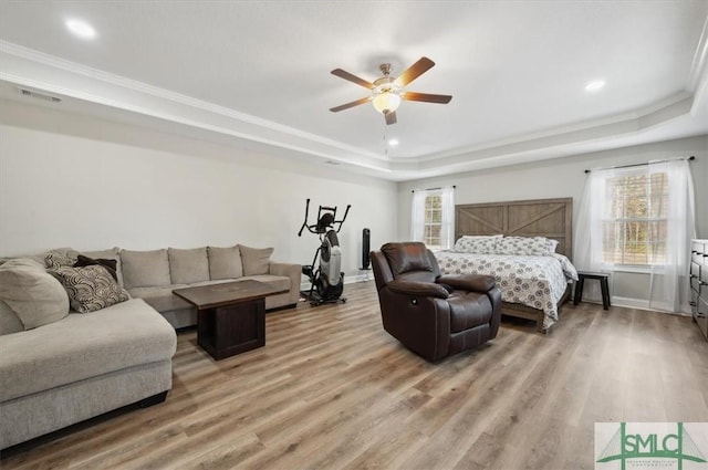 bedroom with hardwood / wood-style floors, crown molding, a raised ceiling, and ceiling fan