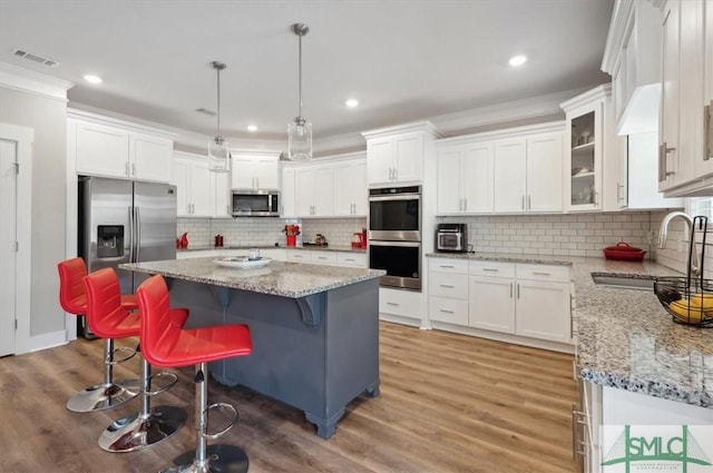 kitchen featuring sink, a kitchen island, white cabinets, and appliances with stainless steel finishes