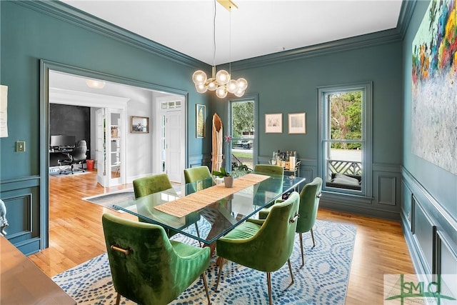 dining area with ornamental molding, a chandelier, and light wood-type flooring