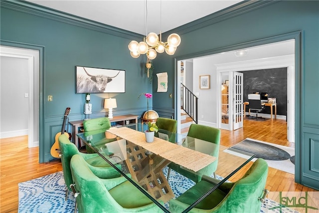 dining area featuring an inviting chandelier, crown molding, light hardwood / wood-style flooring, and french doors