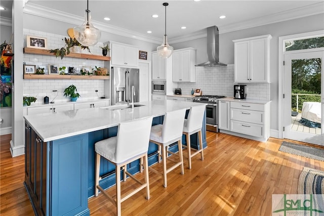 kitchen featuring a breakfast bar, hanging light fixtures, wall chimney range hood, stainless steel appliances, and white cabinets