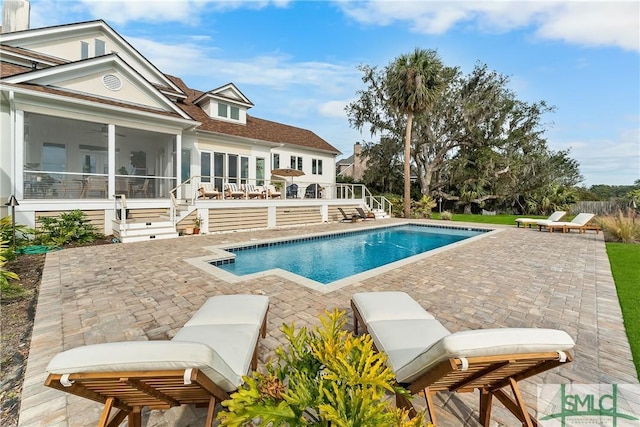 view of swimming pool with a patio area and a sunroom