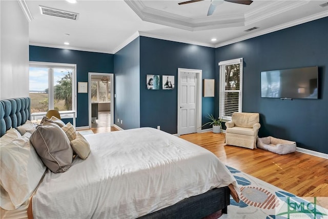 bedroom featuring ceiling fan, ornamental molding, a raised ceiling, and light hardwood / wood-style flooring