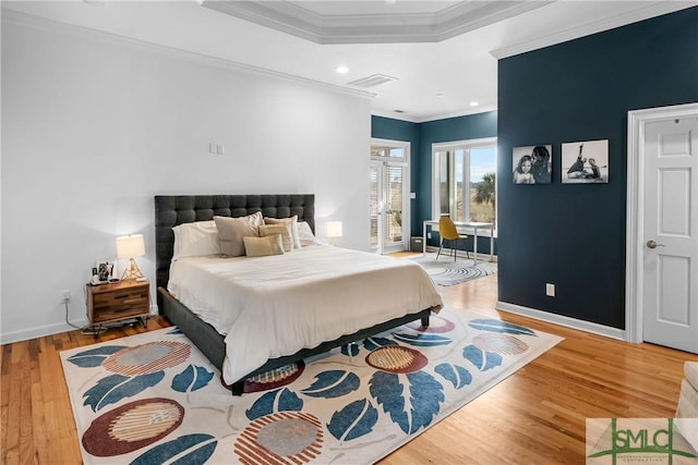 bedroom with a raised ceiling, crown molding, and hardwood / wood-style floors