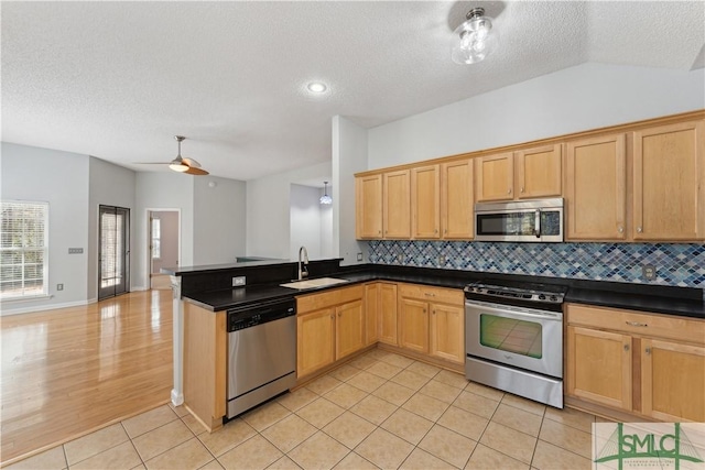 kitchen with lofted ceiling, sink, light tile patterned floors, stainless steel appliances, and decorative backsplash