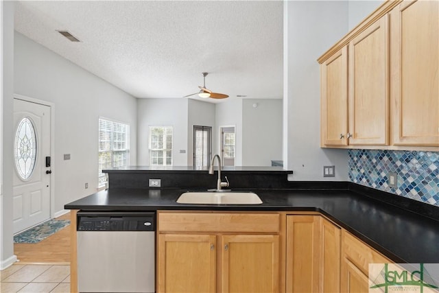 kitchen featuring light brown cabinetry, sink, a textured ceiling, light tile patterned floors, and stainless steel dishwasher