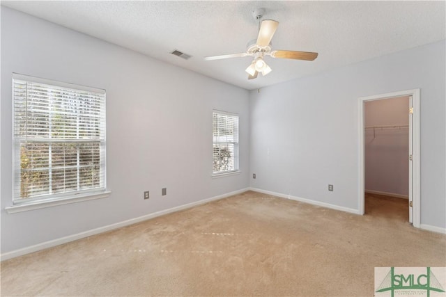 spare room featuring light carpet, a textured ceiling, and ceiling fan