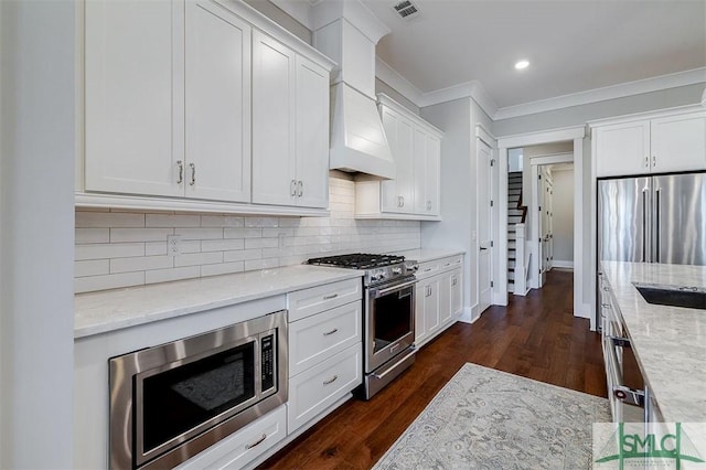 kitchen with ornamental molding, stainless steel appliances, light stone countertops, and white cabinets