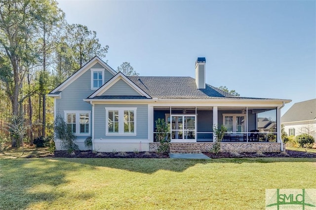 rear view of house featuring a yard and a sunroom