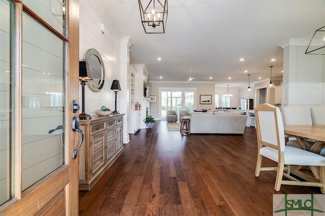 foyer entrance with ornamental molding, dark wood-type flooring, and ceiling fan with notable chandelier