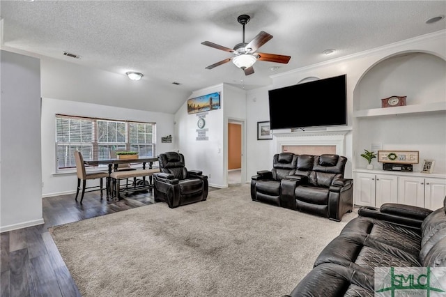 living room featuring lofted ceiling, dark hardwood / wood-style flooring, ornamental molding, ceiling fan, and a textured ceiling