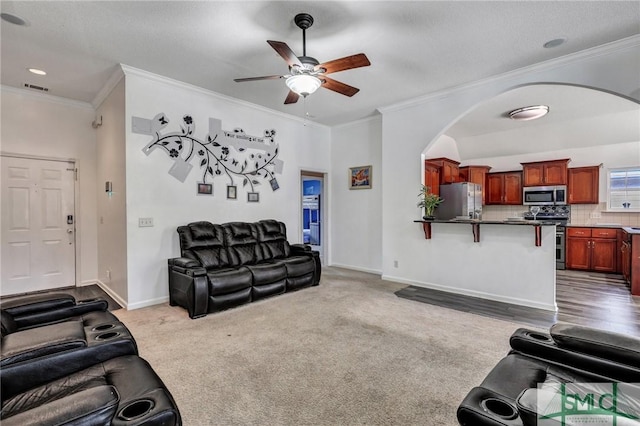 living room with ornamental molding, ceiling fan, and carpet