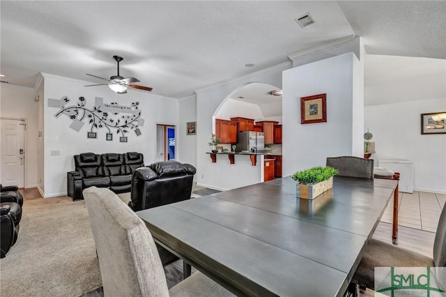 dining space with ceiling fan, light colored carpet, ornamental molding, and a textured ceiling