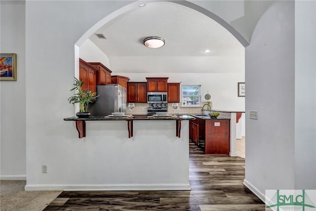 kitchen with sink, appliances with stainless steel finishes, dark hardwood / wood-style flooring, decorative backsplash, and kitchen peninsula