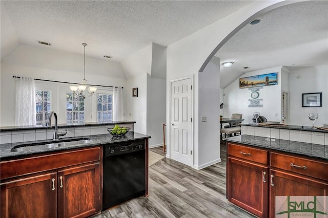 kitchen with sink, vaulted ceiling, hanging light fixtures, dark stone countertops, and black dishwasher