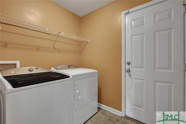 laundry room featuring washing machine and clothes dryer, a textured ceiling, and light tile patterned floors