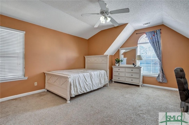 bedroom featuring light carpet, ceiling fan, vaulted ceiling, and a textured ceiling