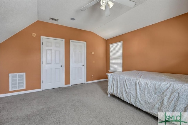 carpeted bedroom featuring lofted ceiling, a textured ceiling, and ceiling fan