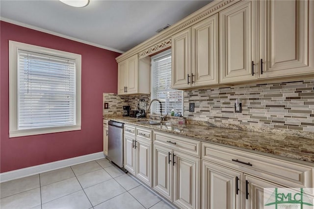 kitchen with light tile patterned flooring, sink, dishwasher, light stone countertops, and cream cabinets