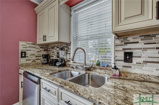 kitchen with sink, dishwasher, light stone countertops, cream cabinets, and decorative backsplash