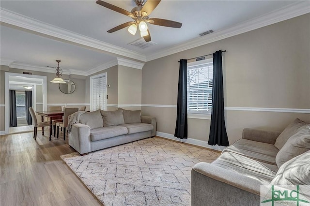 living room with crown molding, ceiling fan, and light wood-type flooring