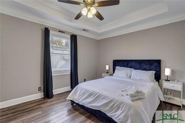 bedroom featuring a tray ceiling, wood-type flooring, ornamental molding, and ceiling fan