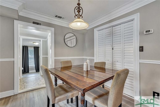 dining room with hardwood / wood-style flooring and ornamental molding