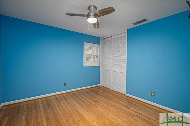 unfurnished bedroom with ceiling fan, light hardwood / wood-style flooring, a closet, and a textured ceiling