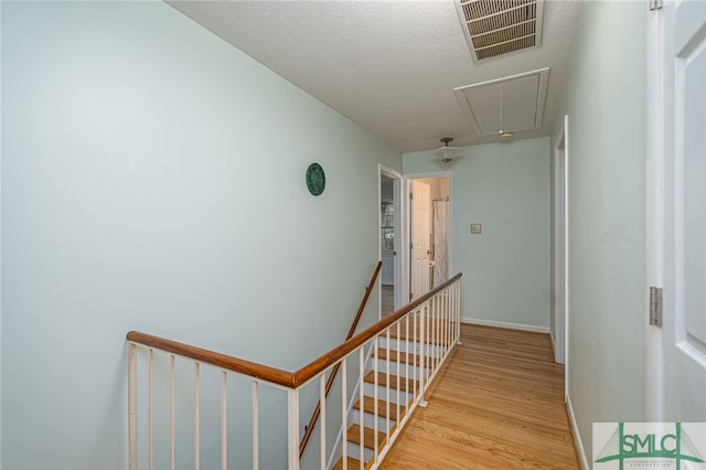 hall featuring light hardwood / wood-style floors and a textured ceiling