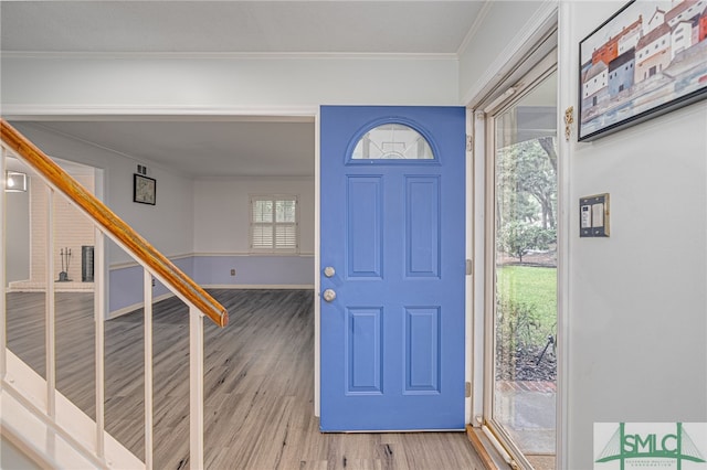 foyer entrance with crown molding and light wood-type flooring